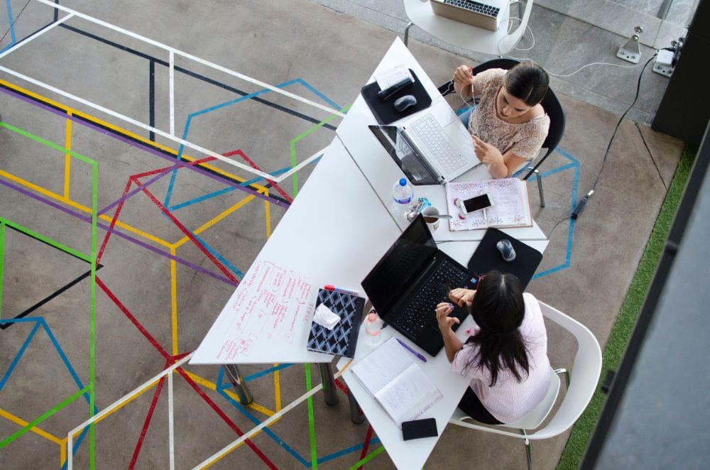 SEO consulting services two ladies discussing work on a brightly coloured table