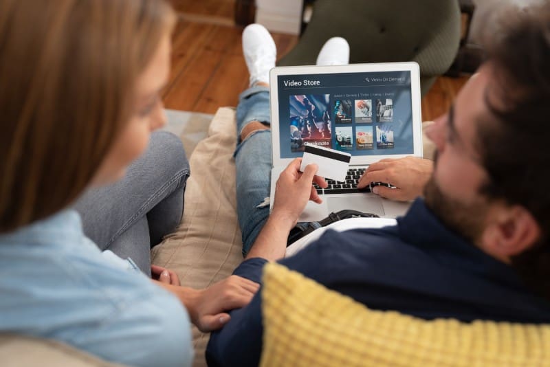 Man buying goods on his mobile device sat of sofa with credit card