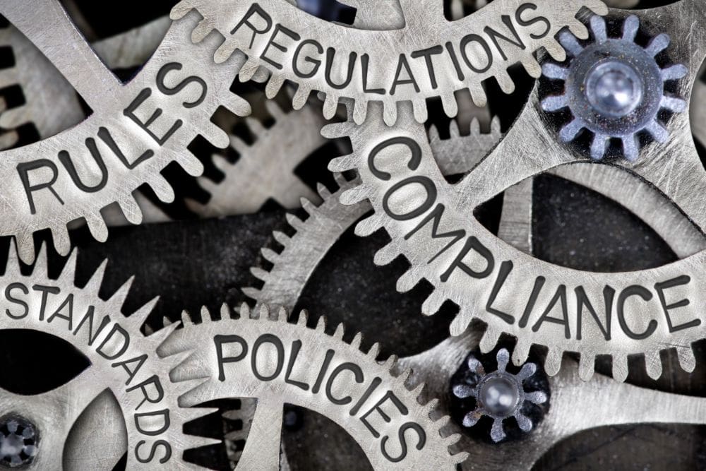 Cog wheels with the words compliance, rules, policies. Regulations and standards